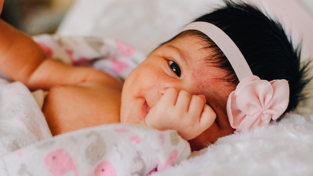 A baby girl hiding her face.