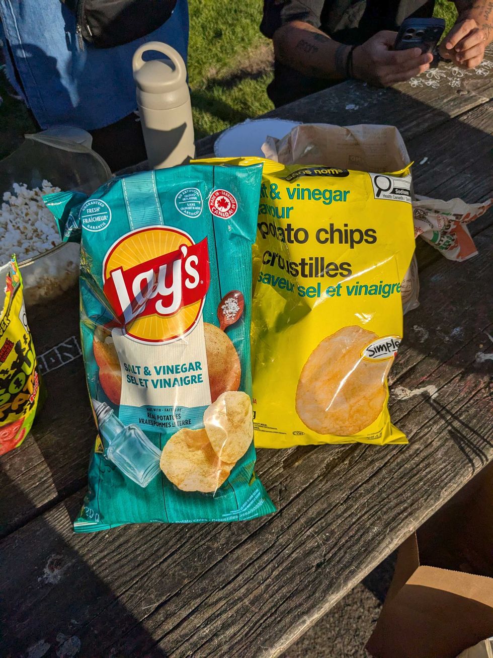 A bag of Lays and No Name salt and vinegar chips on a picnic table
