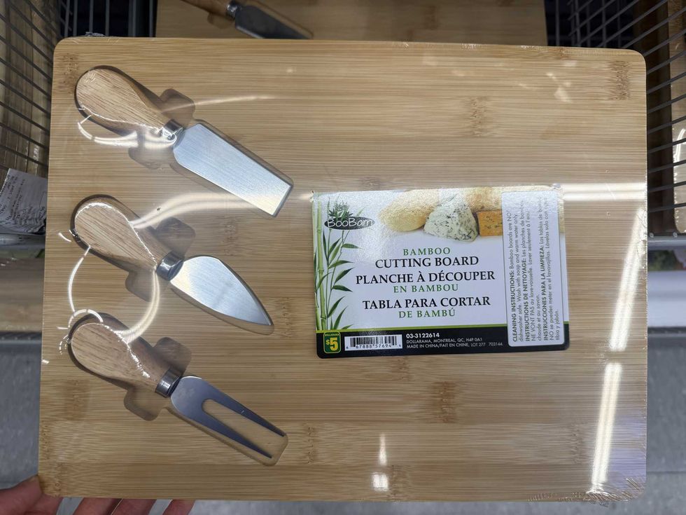 A bamboo cutting board with three cheese knives.