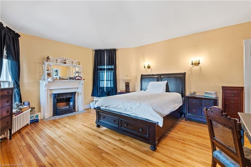 A bedroom with a fireplace and yellow walls.