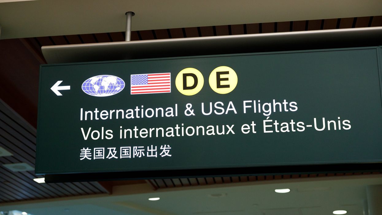 A bilingual airport sign directs passengers to international and U.S. flights.