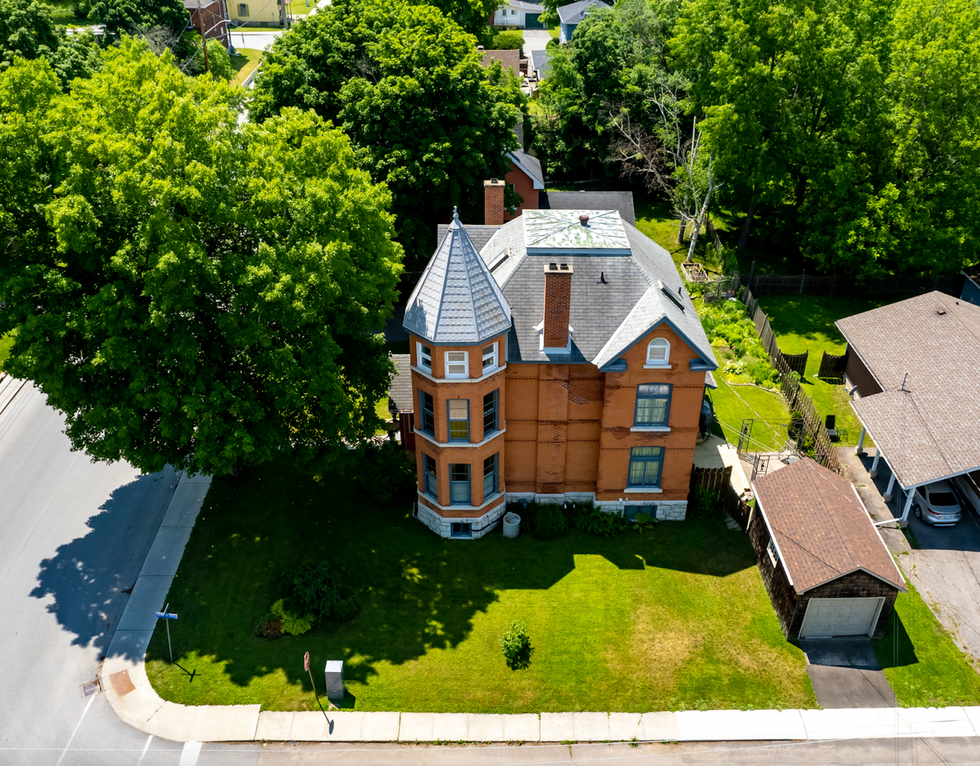 A bird's-eye view of the mansion which is surrounded by green grass and tall trees.