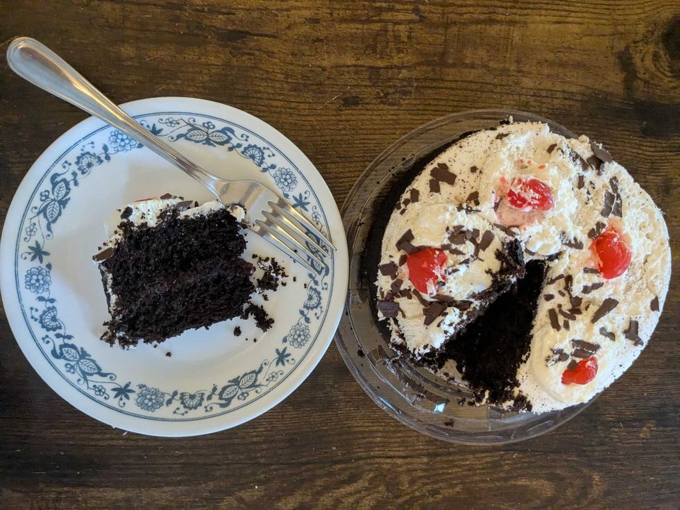 A black forest cake with a slice taken out and on a plate next to it.