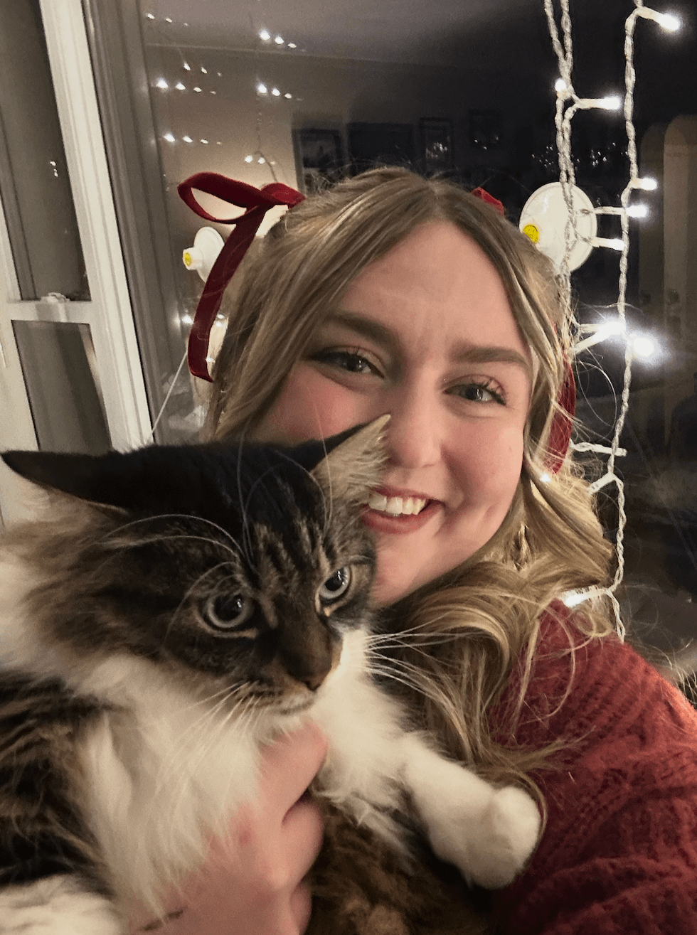 A blond woman cuddling a fluffy cat.