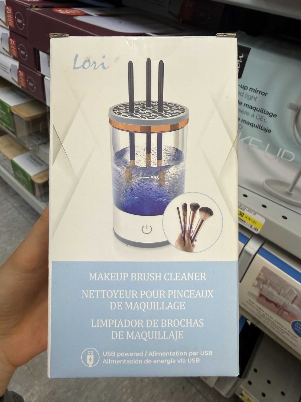 A blue and white box with a picture of a round device that has water and makeup brushes being cleaned in it on the front and the label says makeup brush cleaner.