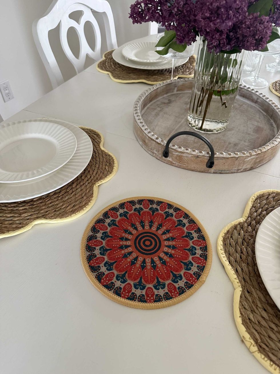 A blue, beige and orange round mat on a white dining table.