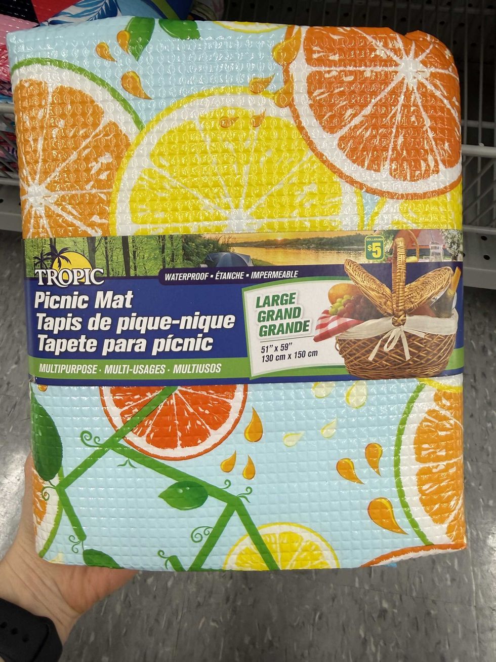 A blue mat with citrus fruit on it and a label that says Tropic Picnic Mat.