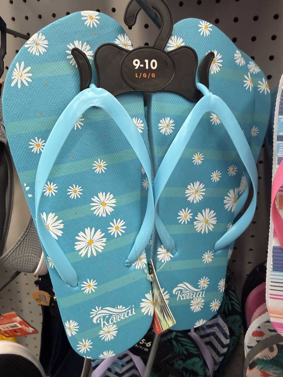 A blue pair of flip flops with white daisies on them.