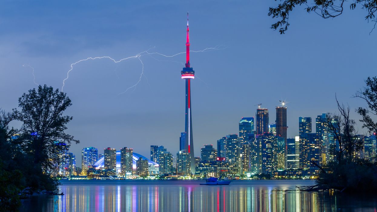 A bolt of lightning behind Toronto's skyline in a dark sky.