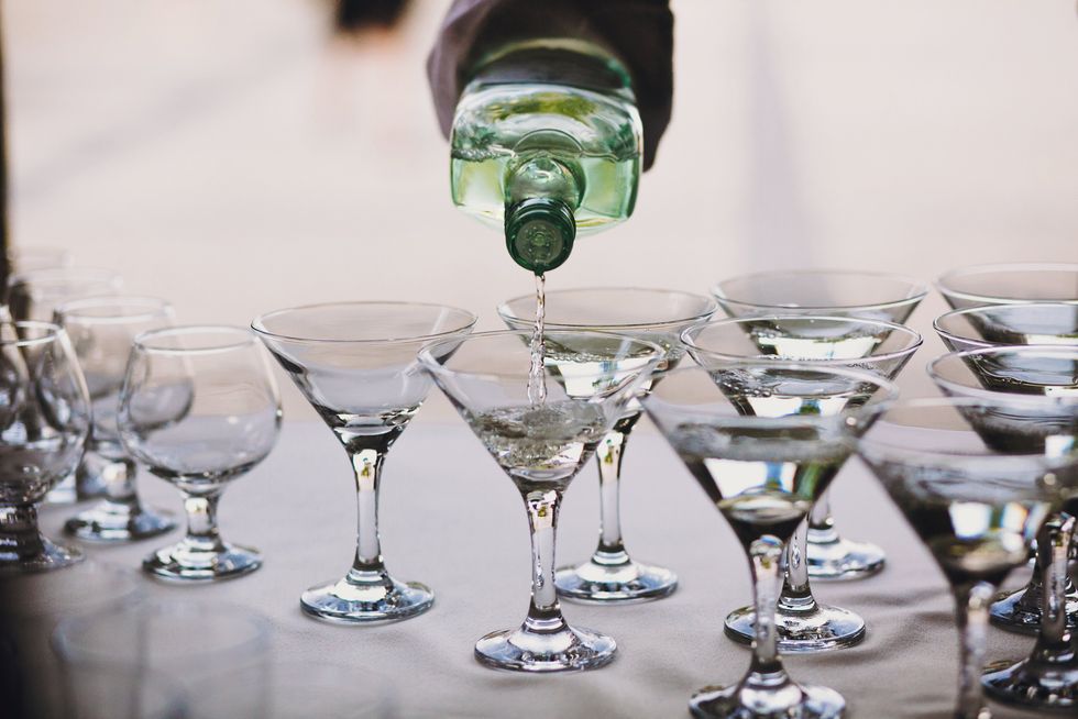 A bottle of alcohol being poured into a martini.