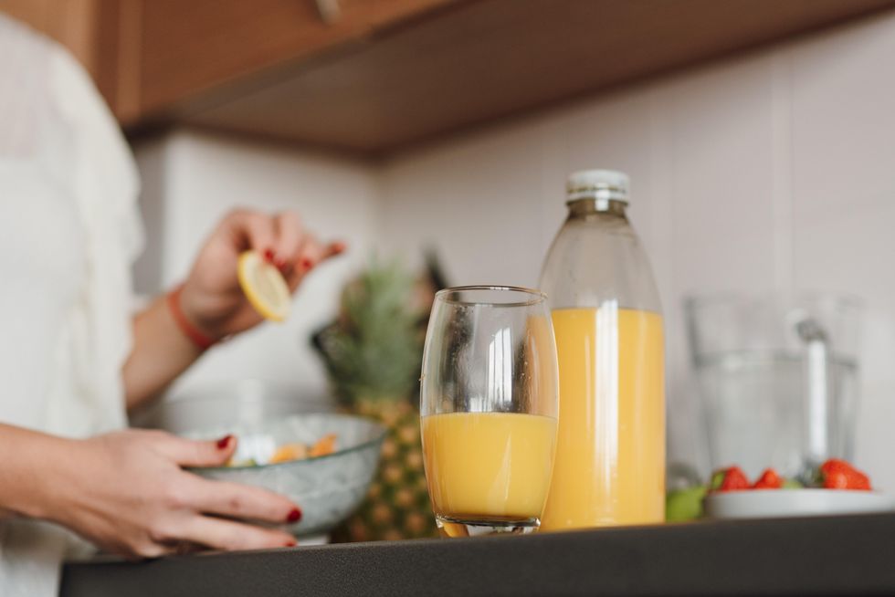 A bottle of orange juice and a glass of orange juice on a countertop