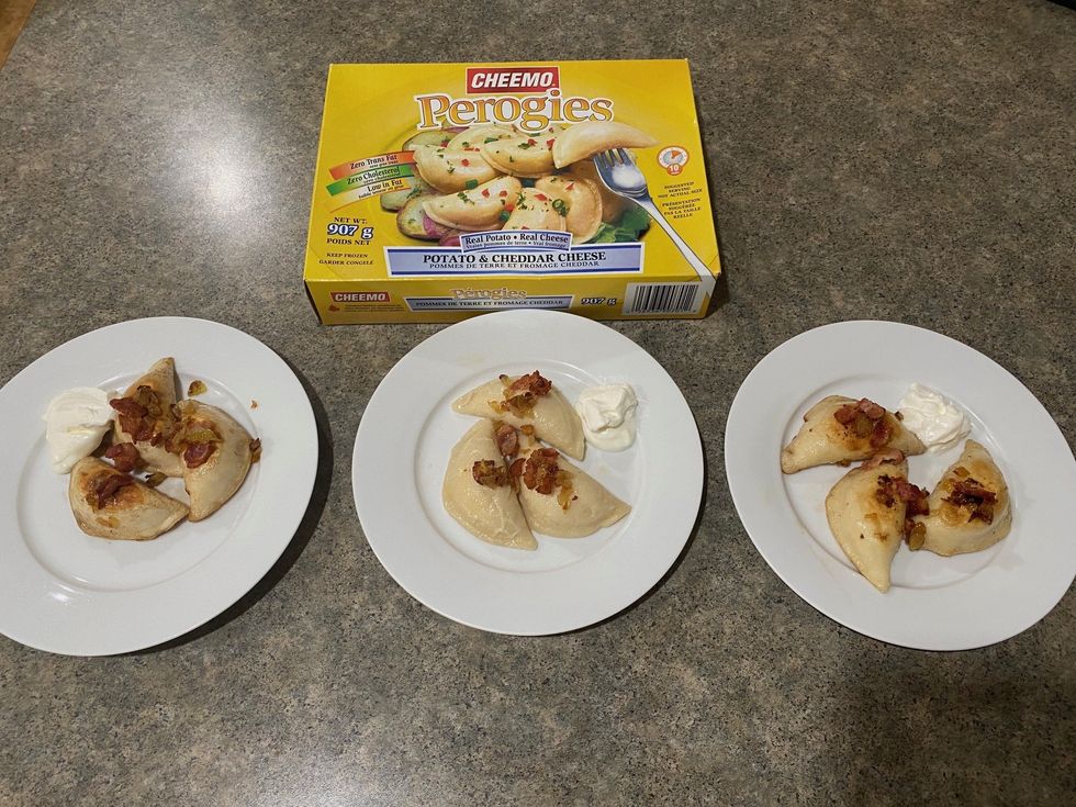 A box of CHEEMO Potato & Cheddar Cheese Perogies and three plates of cooked pierogi.