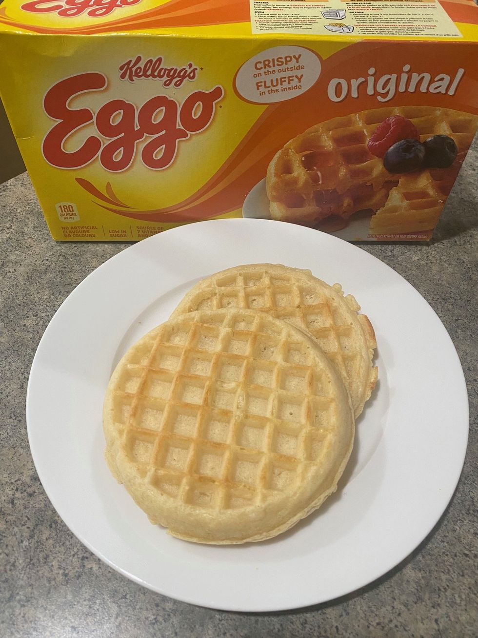 A box of Kellogg's Eggo waffles and two toasted waffles on a plate.
