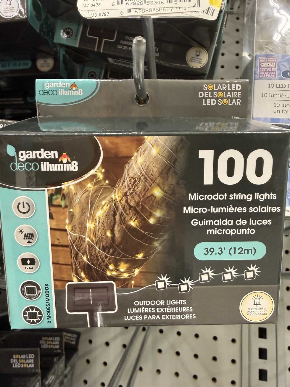 A box that shows string lights on a tree trunk for sale on a store shelf.