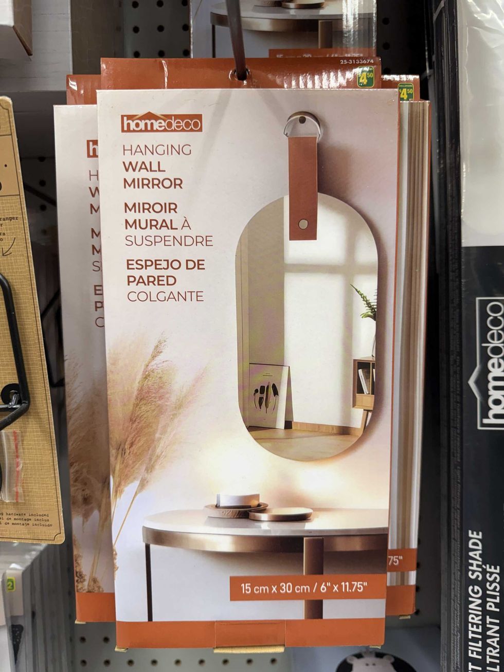 A box with a photo of a hanging wall mirror on the front above a table.