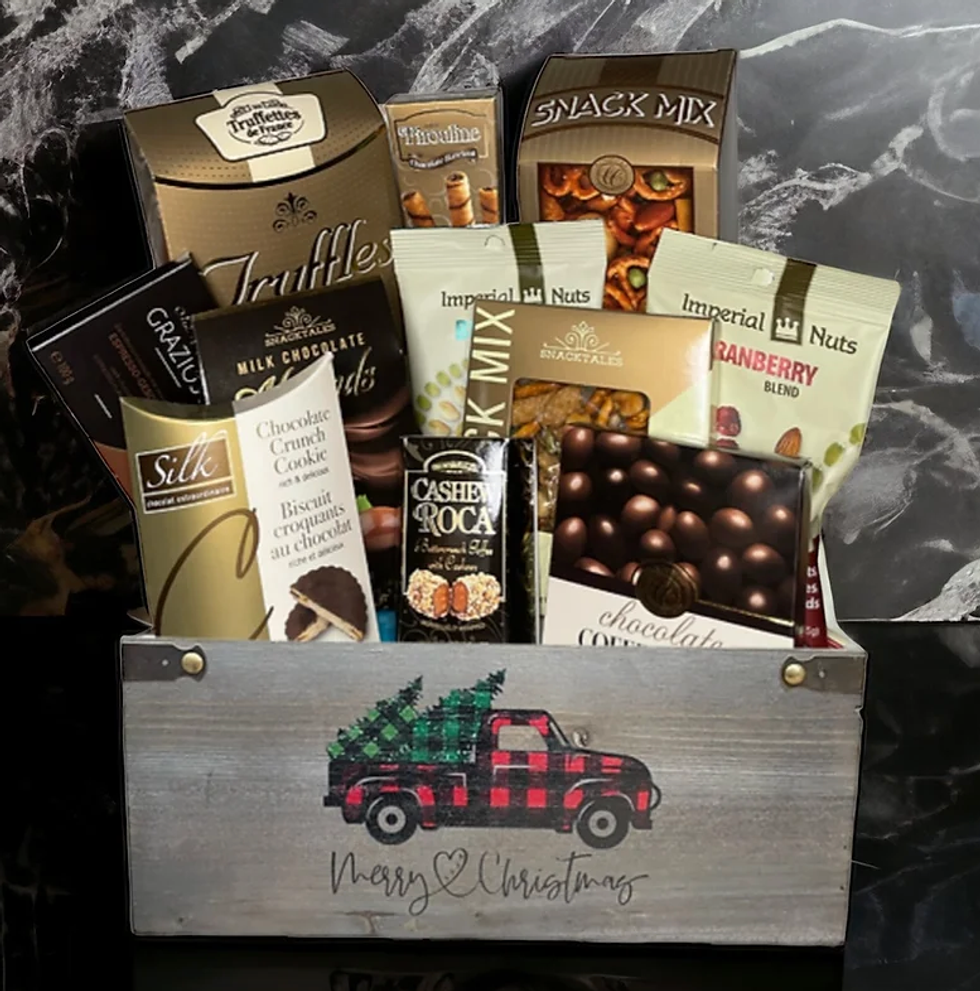A box with a truck and two Christmas trees and writing "Merry Christmas" on it filled with chocolate, cookies, nuts and truffles.