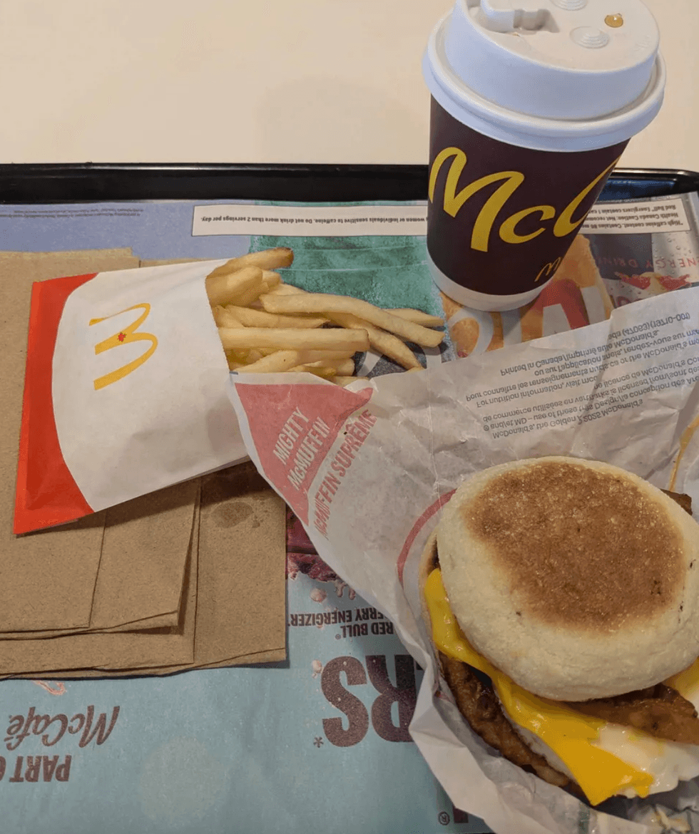 A breakfast sandwich and fries on a table.