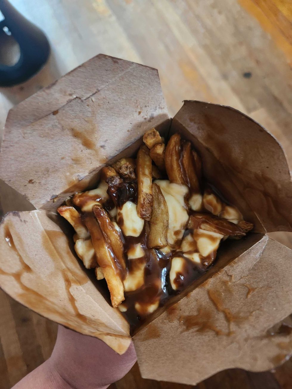 A brown box of poutine wit dark gravy.