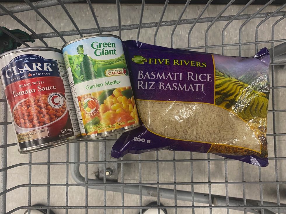 A can of beans, vegetables and basmati rice in a shopping cart.