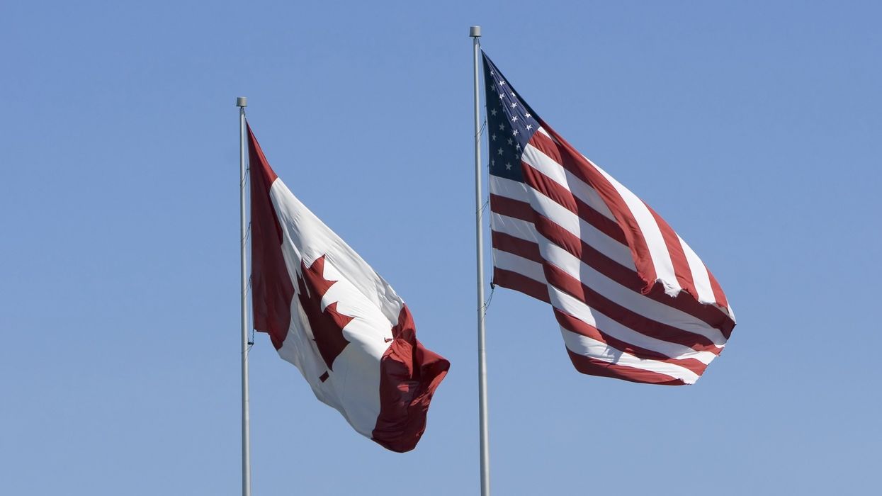 A Canada and U.S. flag with a clear blue sky.