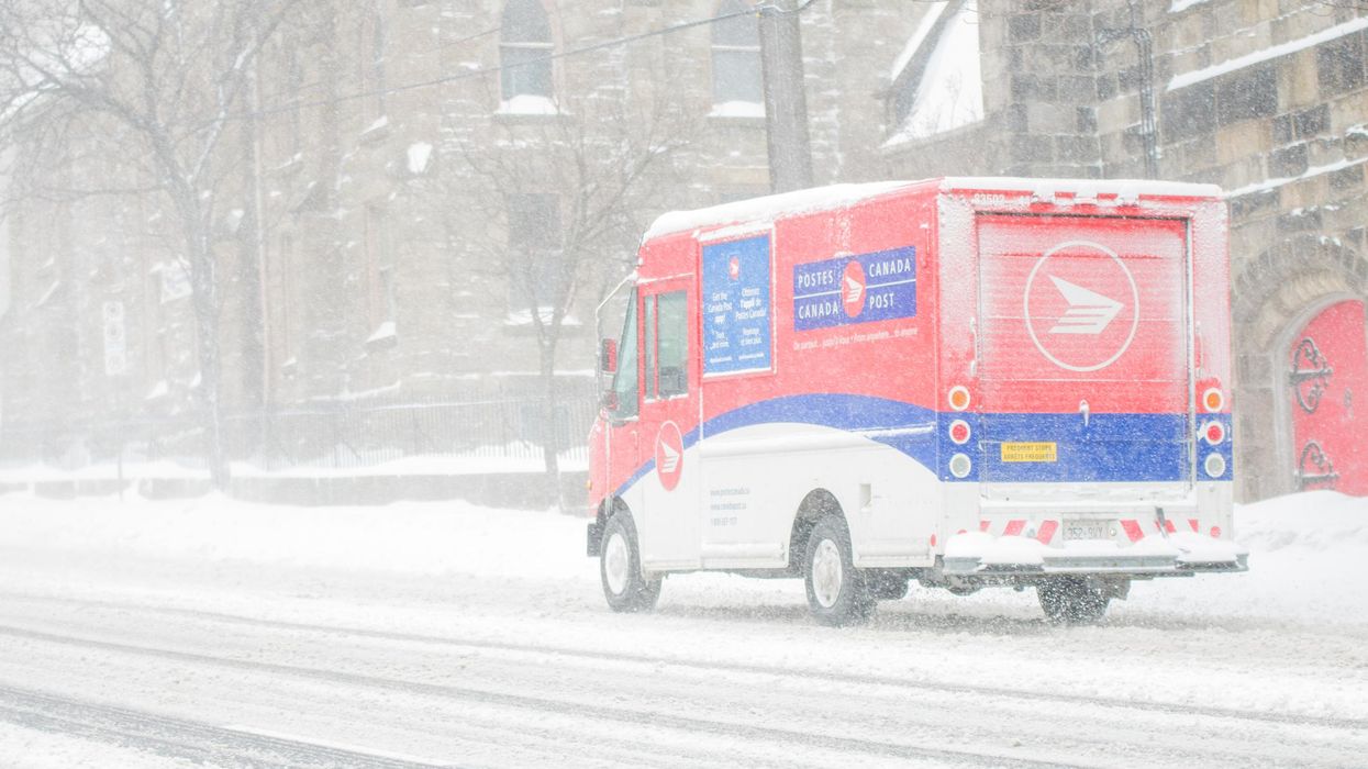 A Canada Post delivery truck driving during a blizzard.