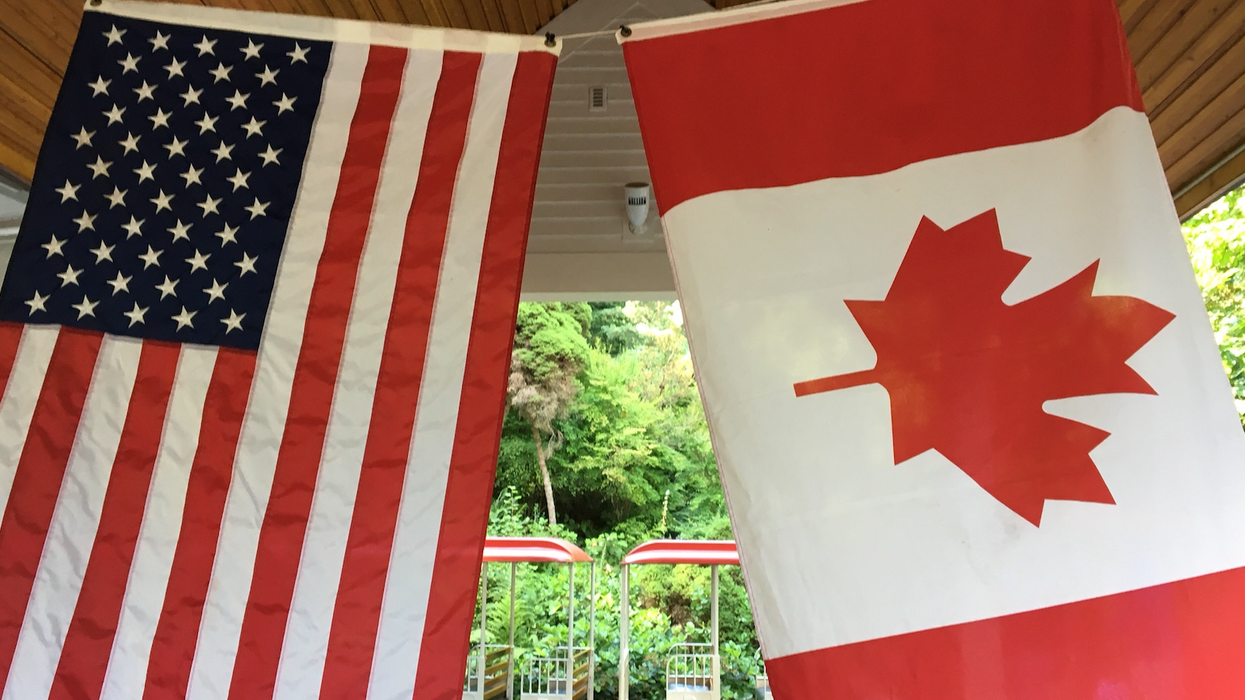 A Canadian flag and a U.S. flag hanging side by side.