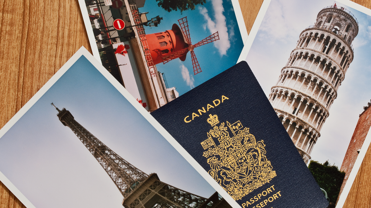 A Canadian passport placed on a wooden surface alongside postcards featuring the Eiffel Tower and the Leaning Tower of Pisa.