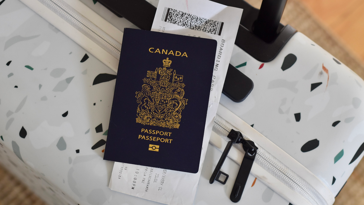 A Canadian passport rests on top of a white suitcase with a terrazzo pattern, along with a boarding pass partially tucked underneath.