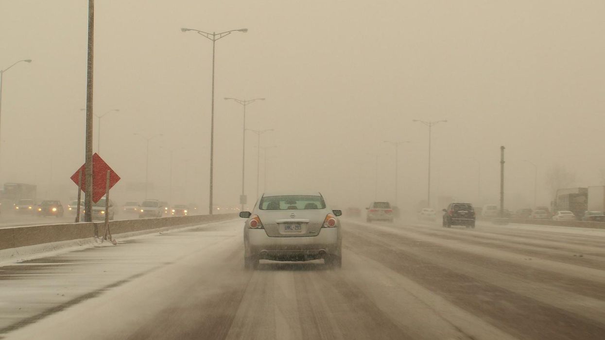 A car driving along a very snowy Highway 401.