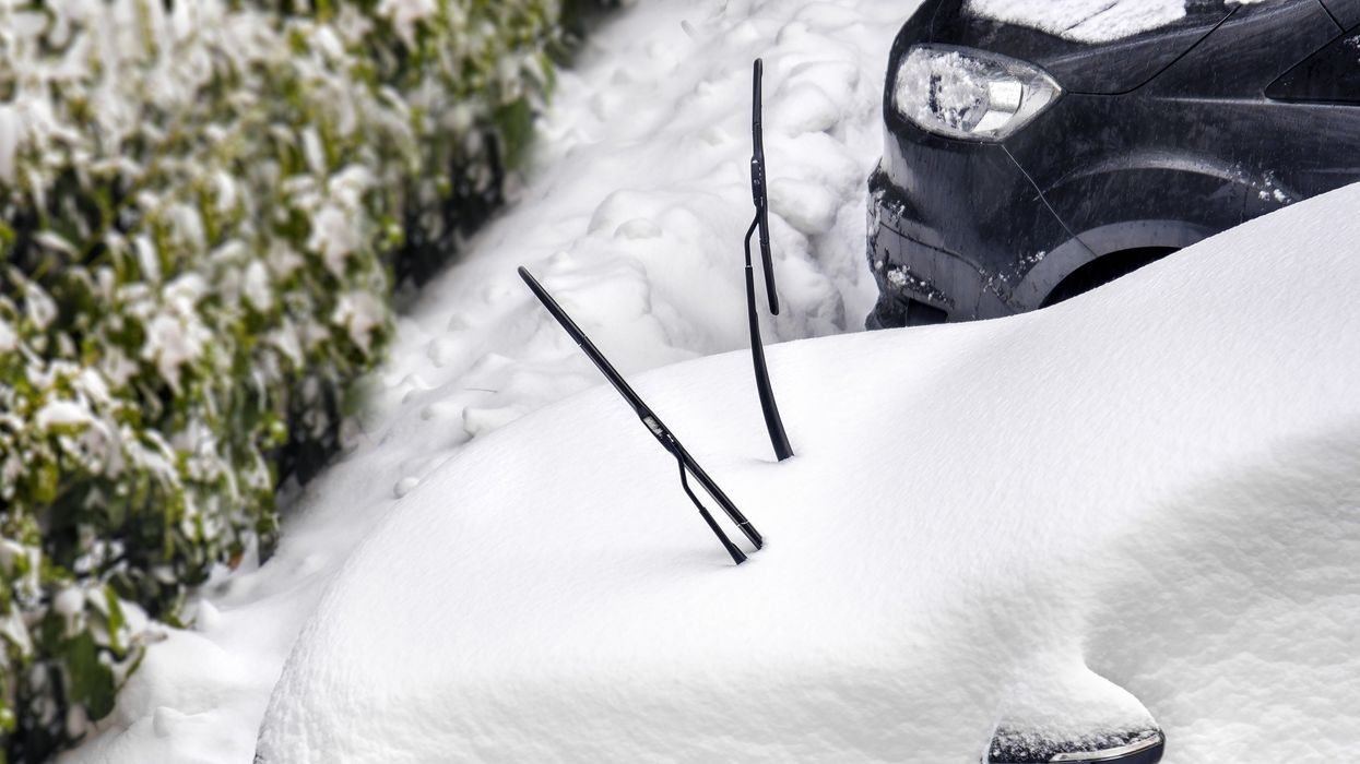 A car with it's windshield wipers up in the snow.