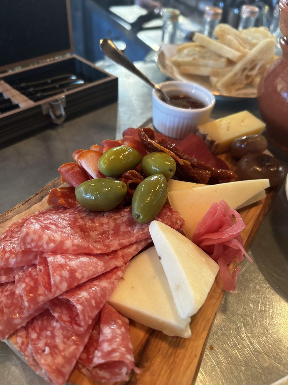 A charcuterie board with various meats, cheeses, olives and condiments.
