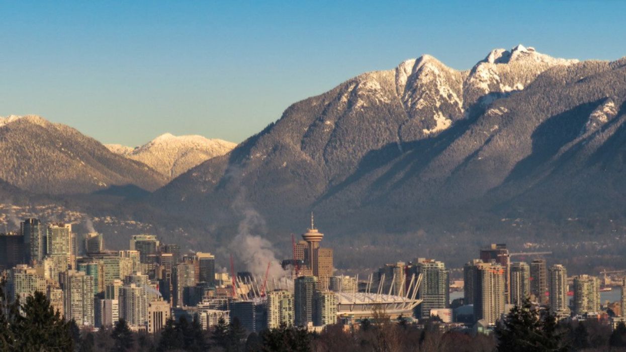 A city surrounded by mountains with snow on the top.