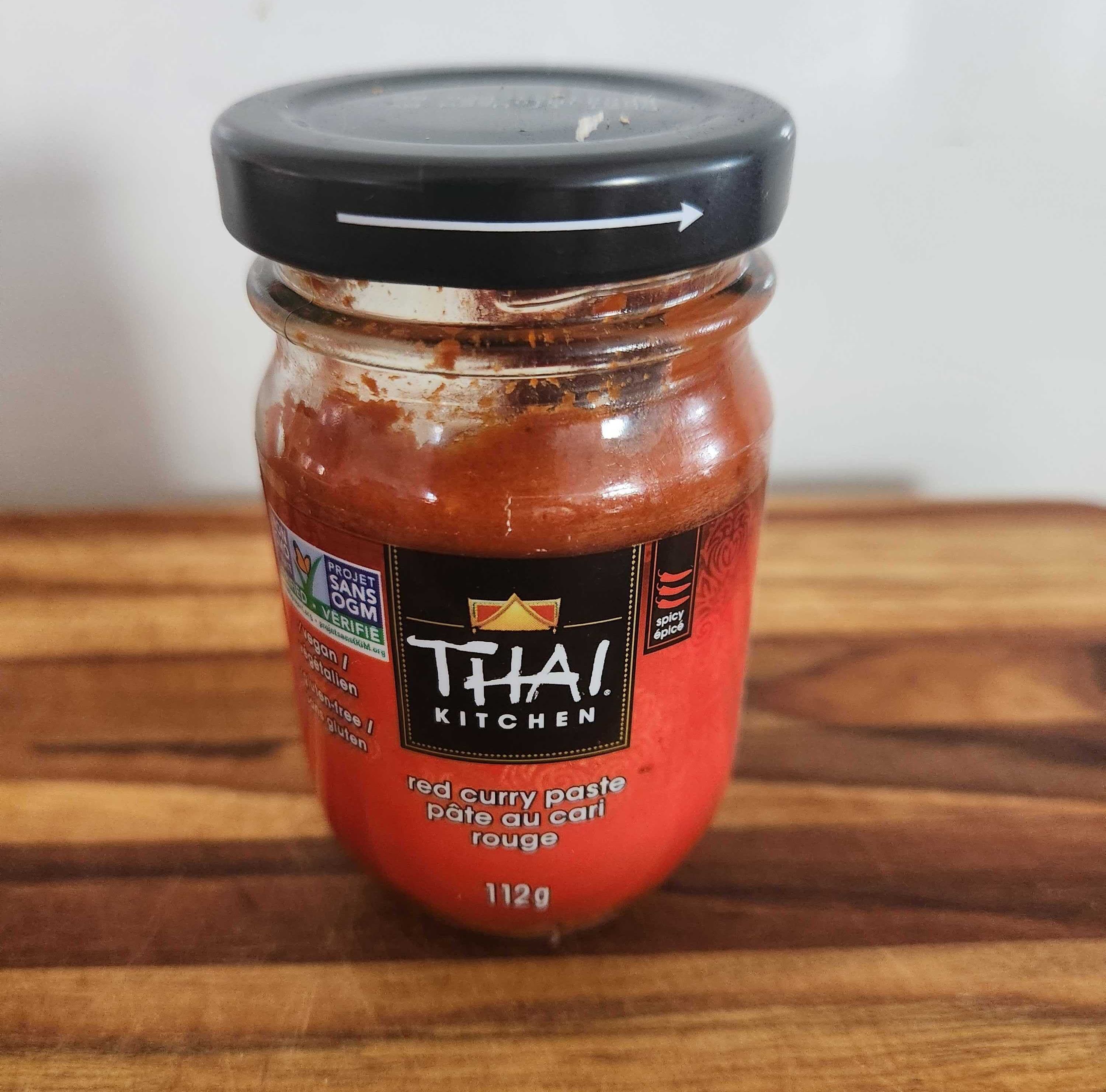 A clear bottle with a red label on a wood cutting board.