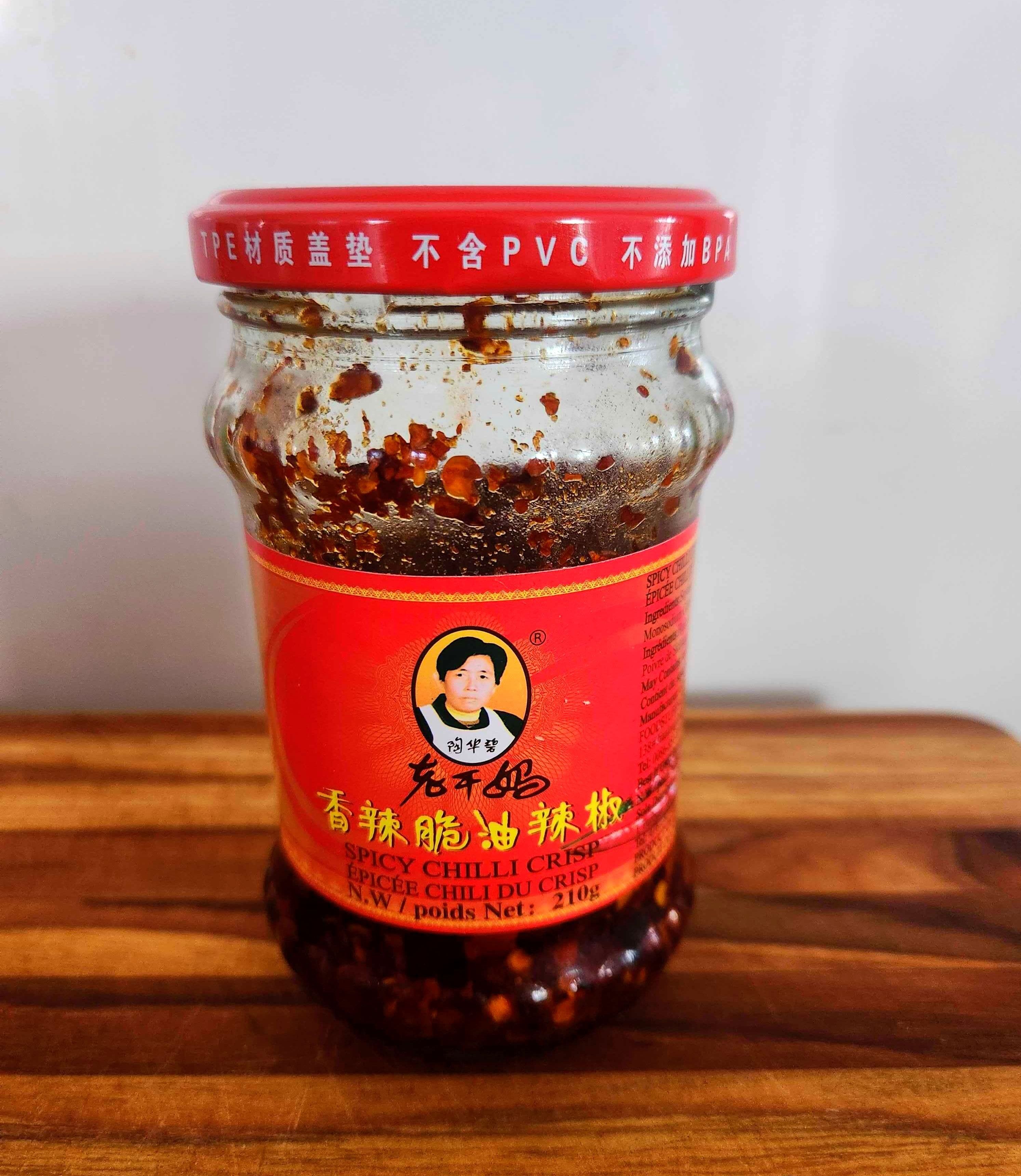 A clear bottle with a red label on a wood cutting board.