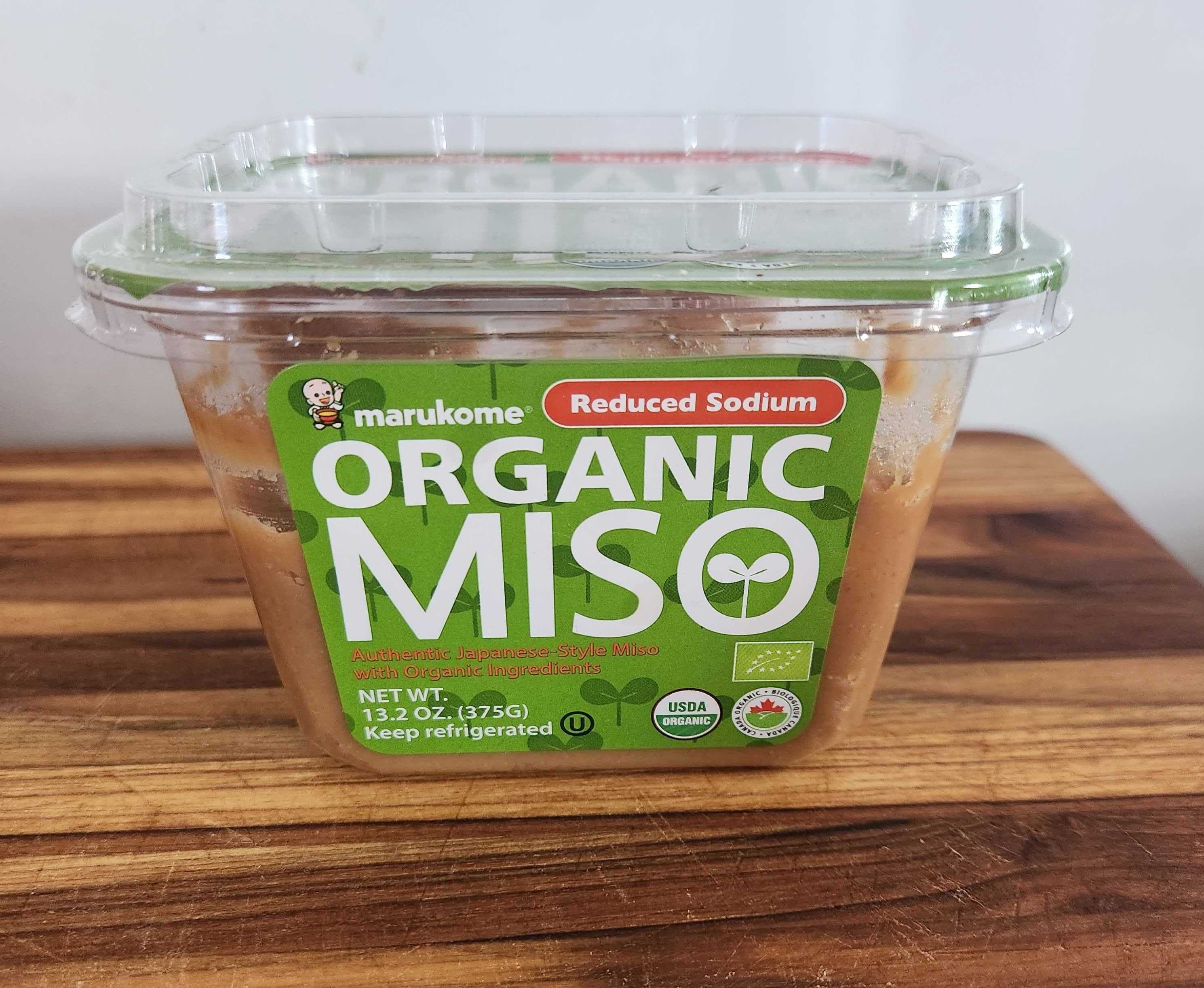 A clear container with a green label on a wood cutting board.