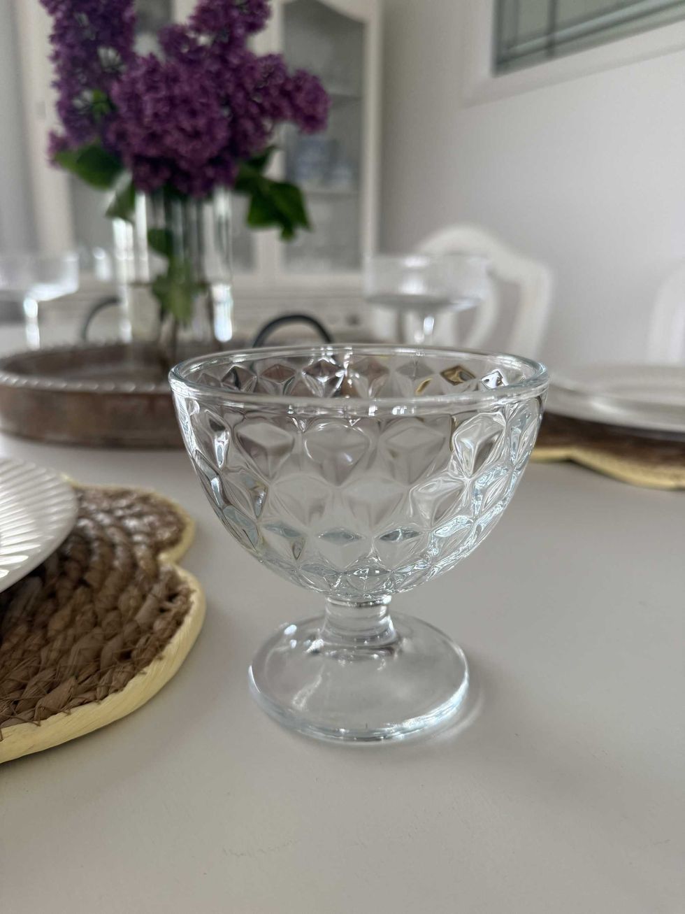 A clear glass cup on a white dining table.