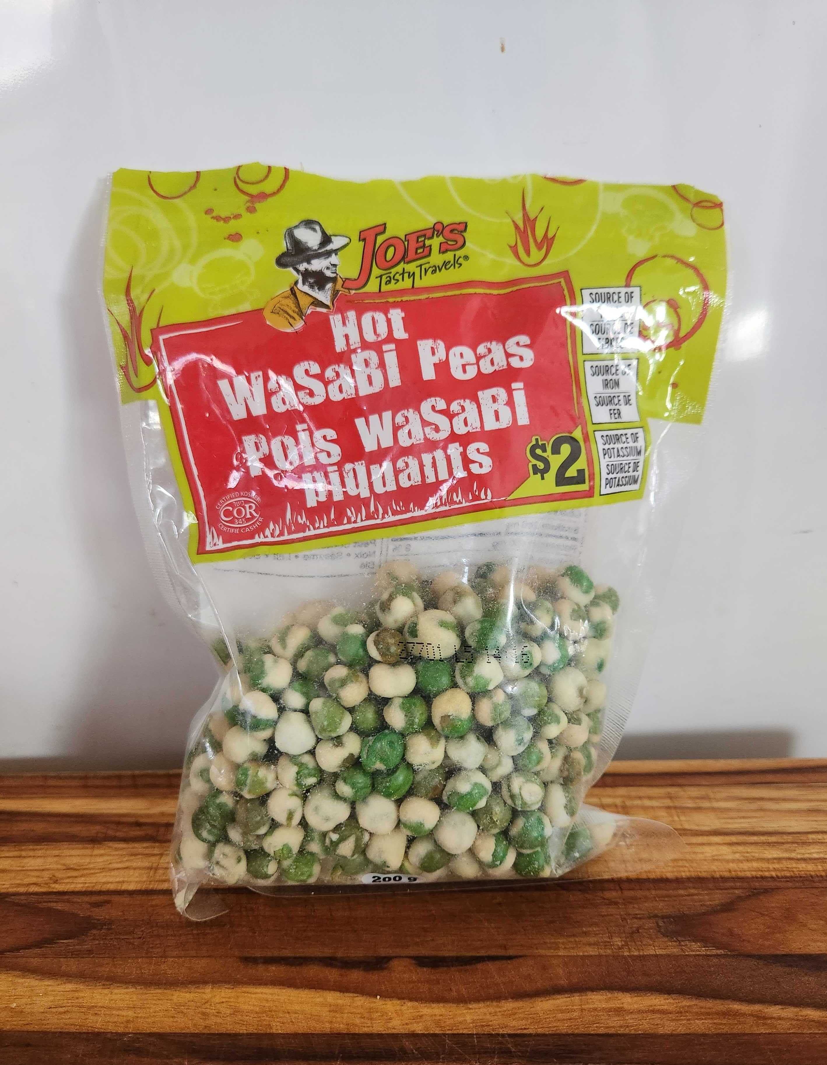 A clear package with round green and white peas in it on a wood cutting board.