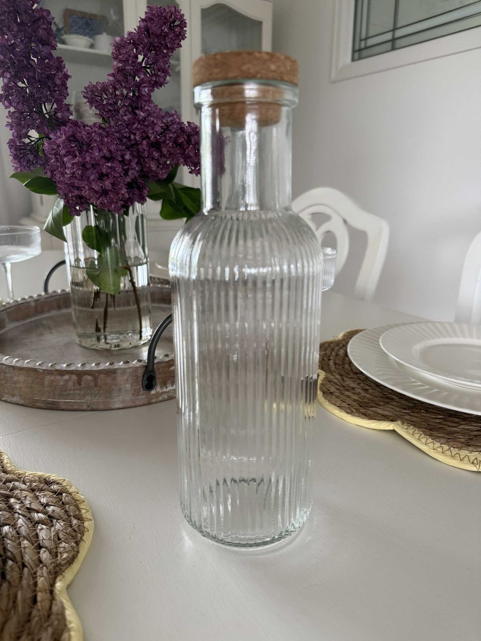 A clear ribbed carafe with a cork on a dining table.