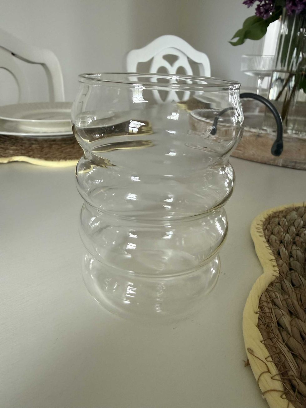 A clear wavy drinking glass sitting on a table.