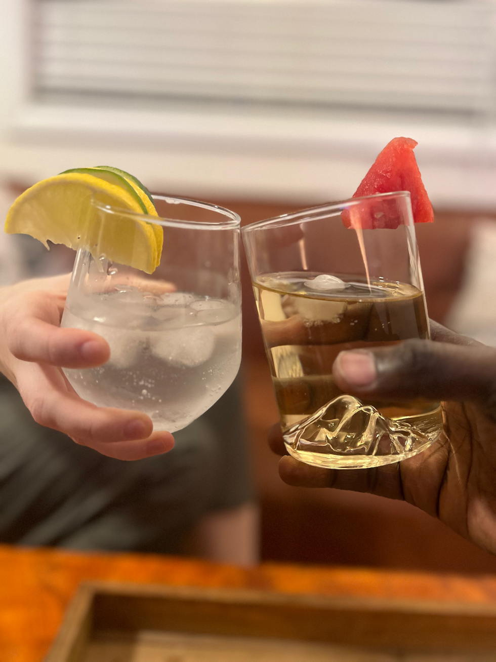 A close-up of two people's hands as they cheers drinks.