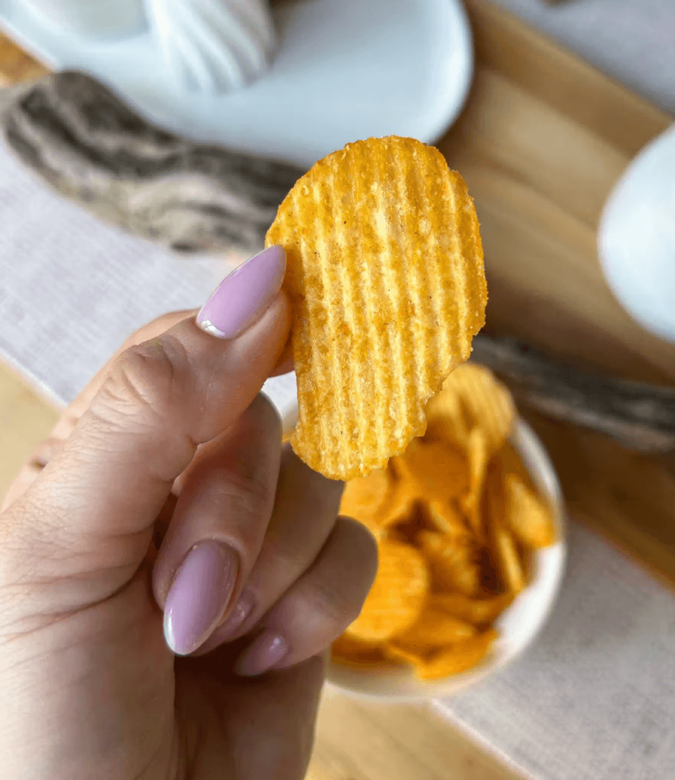 A close up photo of a ruffled all dressed potato chip