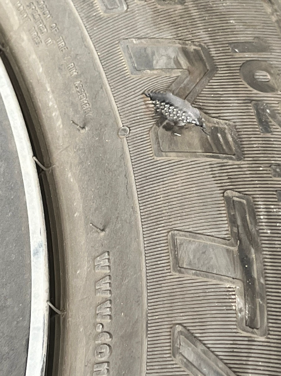 A closeup of the vehicle's front left tire slashed.