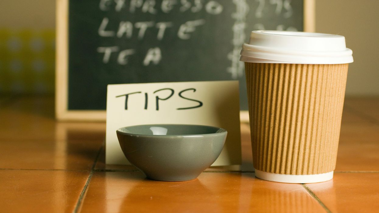 A closeup shot of plastic coffee cup and bowl for tips with a pricelist background