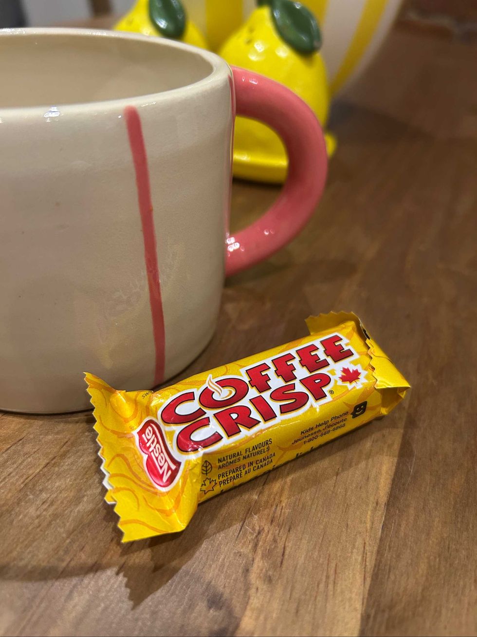 A Coffee Crisp next to a pink striped mug.
