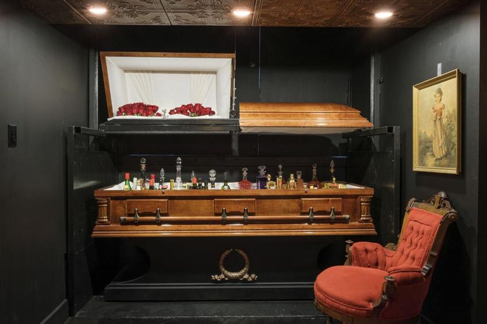 A coffin turned bar in a room painted black.
