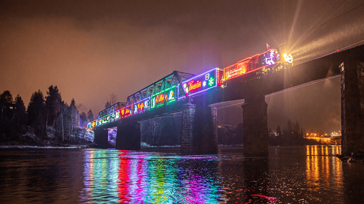 A colourfully lit train travels over a bridge.