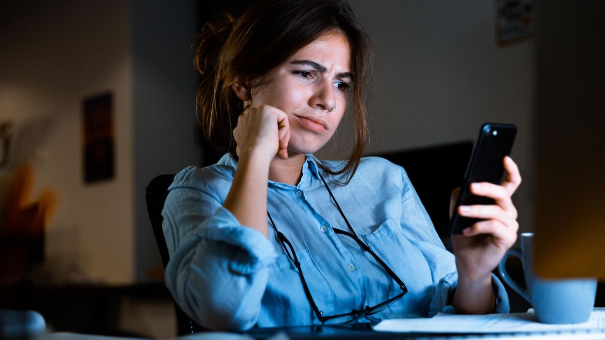 A confused woman looking at her phone.