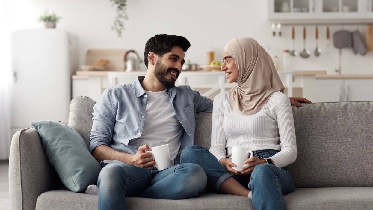 A couple having coffee on a couch.