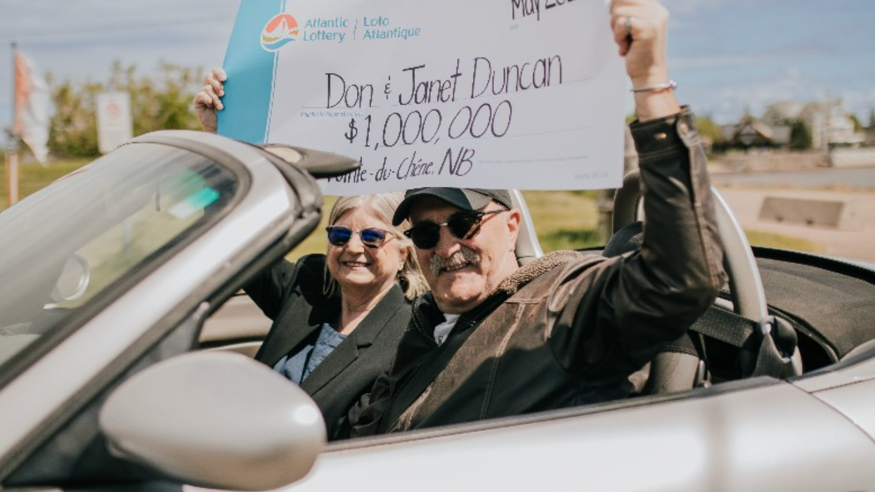 A couple holding a cheque for $1 million.