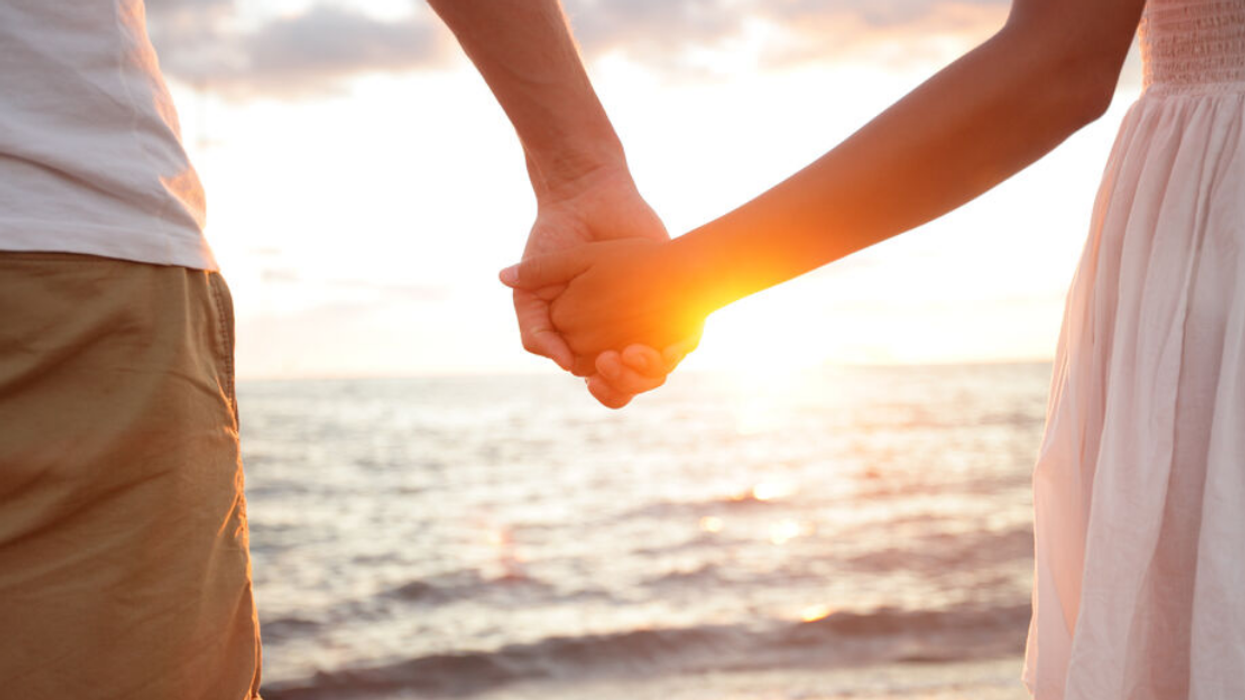 A couple holding hands on the beach.
